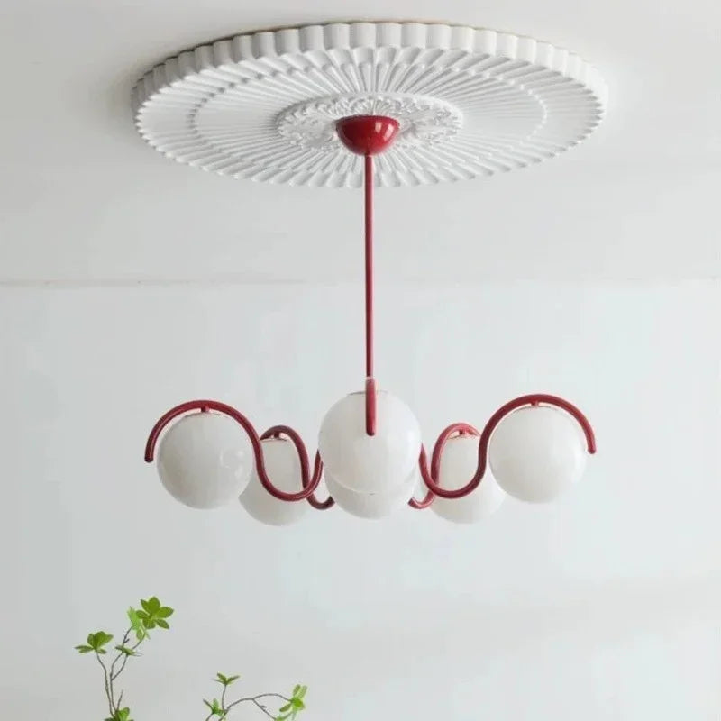 Red curved arms with opal globes under a molded white ceiling rose