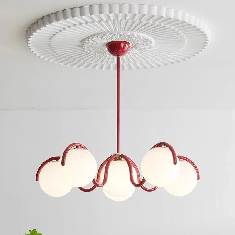 Red arms and six opal globes seen from below against a white ceiling