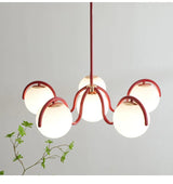 Red arms and globes lit beside a trailing green plant on a pale wall