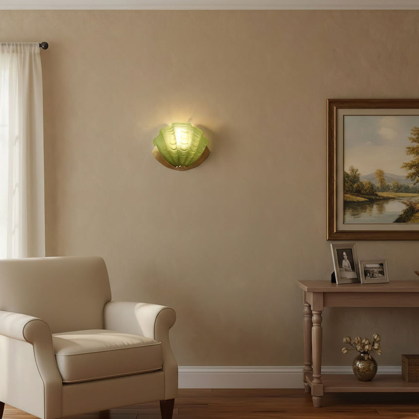 The green shell sconce on a beige wall above an armchair and a console