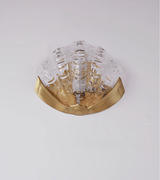 The clear molded glass shade, the fluted ridges visible over the gold bracket