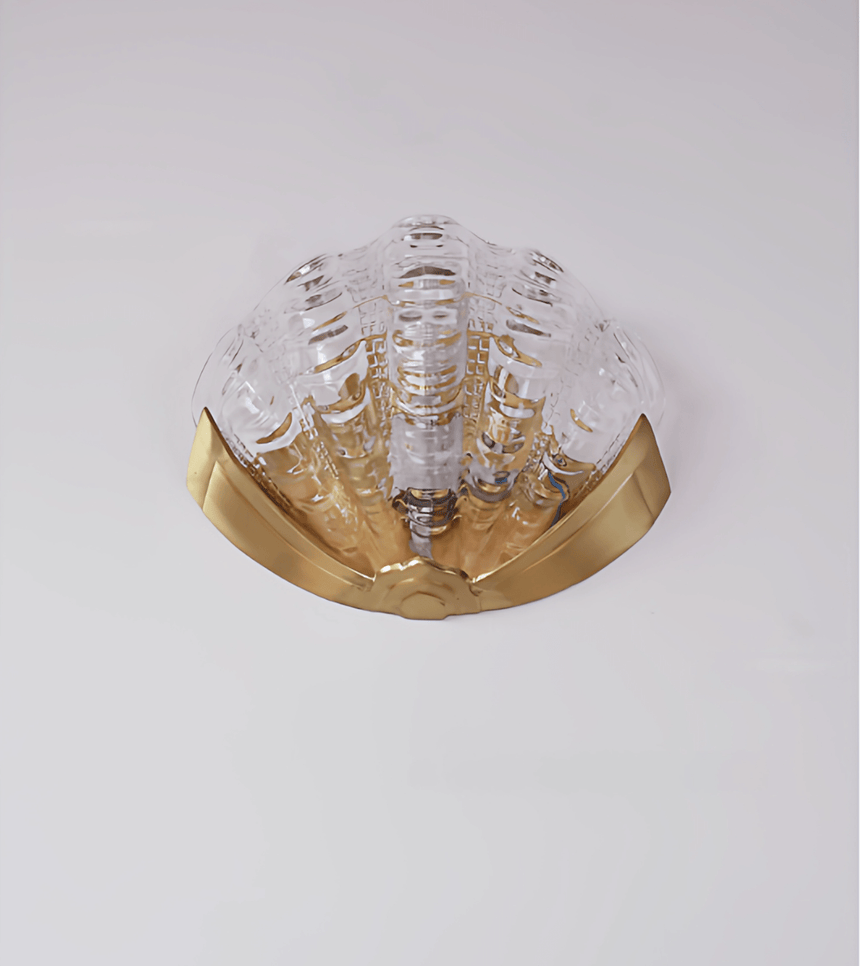 The clear molded glass shade, the fluted ridges visible over the gold bracket