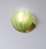The green frosted glass shade lit on a plain wall, the ridges catching light