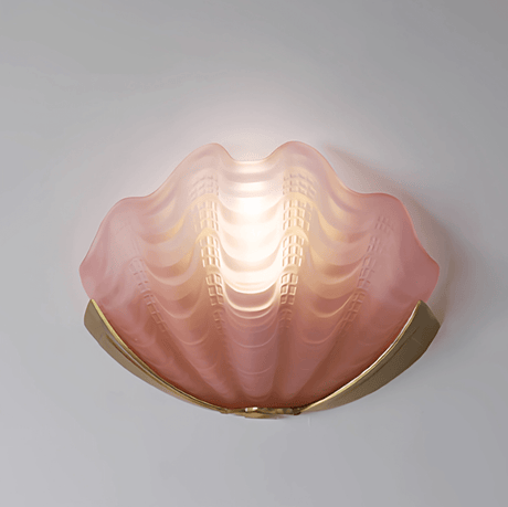 The pink frosted glass shade lit on a plain wall