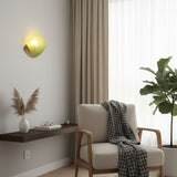 The green shell sconce above a reading chair with a throw and a floating shelf