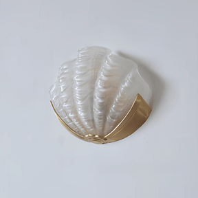 The frosted white glass shade on a plain wall, the gold bracket below