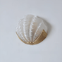 The frosted white glass shade on a plain wall, the gold bracket below