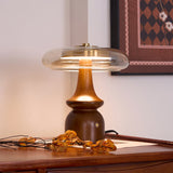 Side table lamp lit on a desk beside a patterned framed picture