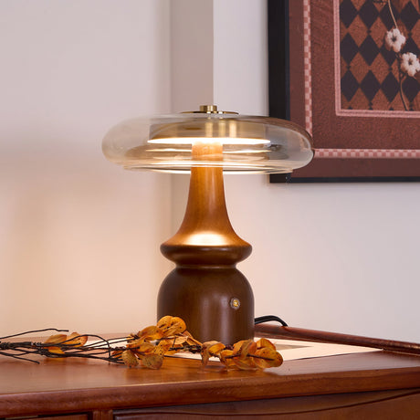 Side table lamp lit on a desk beside a patterned framed picture