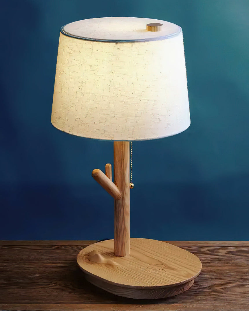 Branch stem side table lamp lit on a wood table against a deep blue wall