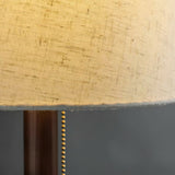 Close view of the lit linen shade edge above the wood branch stem