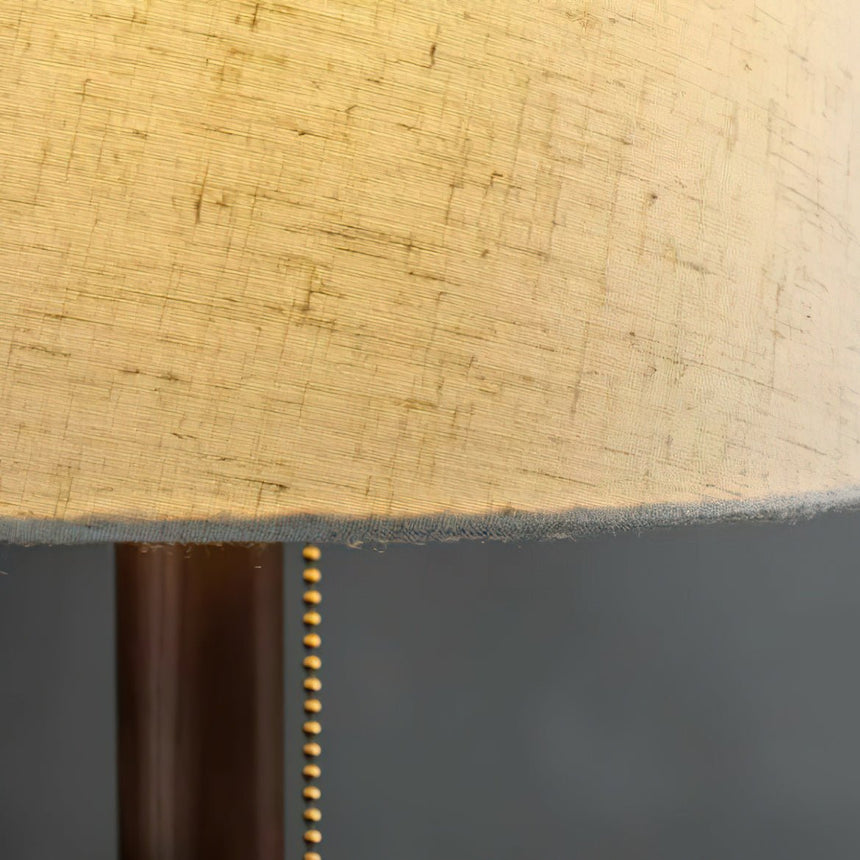 Close view of the lit linen shade edge above the wood branch stem