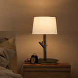 Branch stem lamp lit on a nightstand beside a small round alarm clock