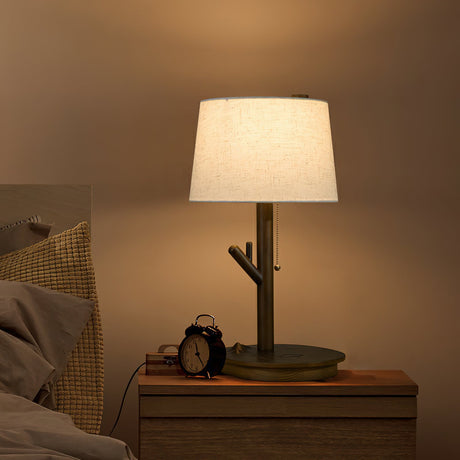 Branch stem lamp lit on a nightstand beside a small round alarm clock