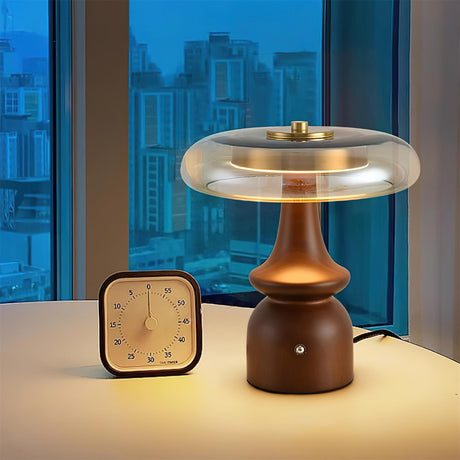 Side table lamp lit at night by a window beside a small clock