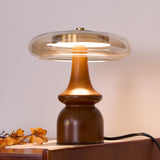 Side table lamp lit close from the front, the amber glass glowing