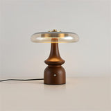 Side table lamp lit against a plain ground with the cord visible