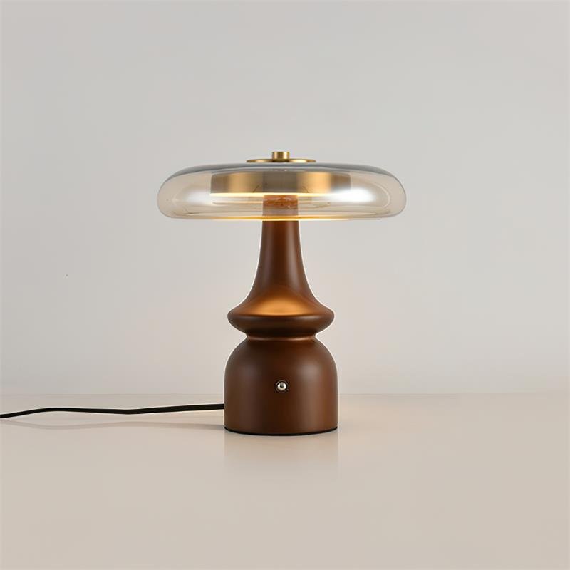 Side table lamp lit against a plain ground with the cord visible