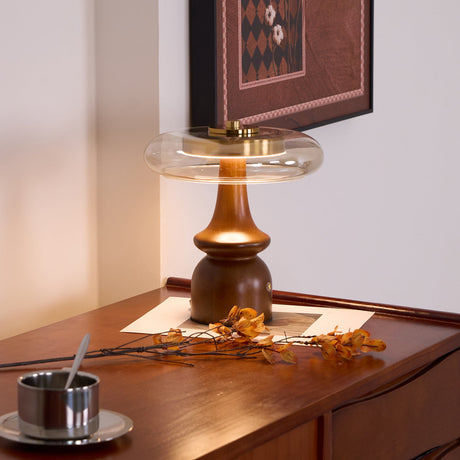 Side table lamp lit on a desk beside a cup and dried flowers