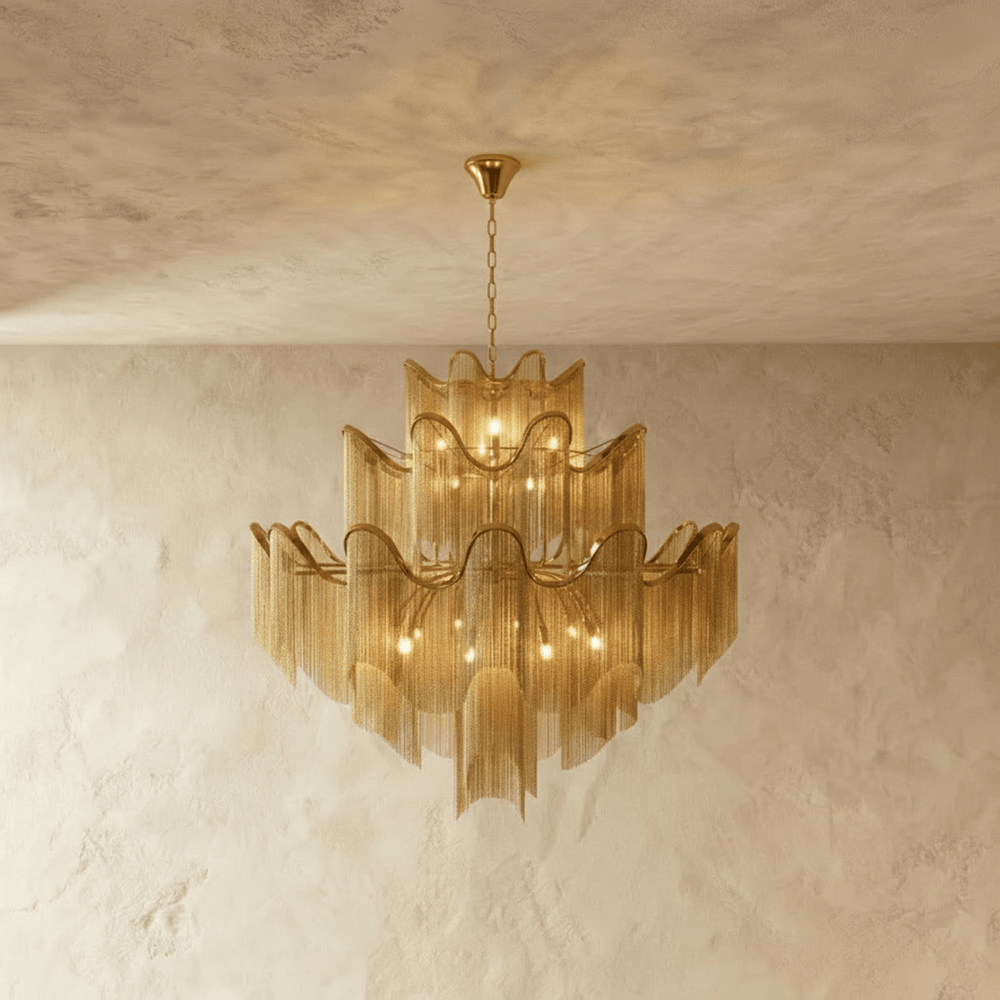 A tiered chandelier of wavy gold bands with fine chain fringe falling below each tier