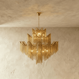 A tiered chandelier of wavy gold bands with fine chain fringe falling below each tier