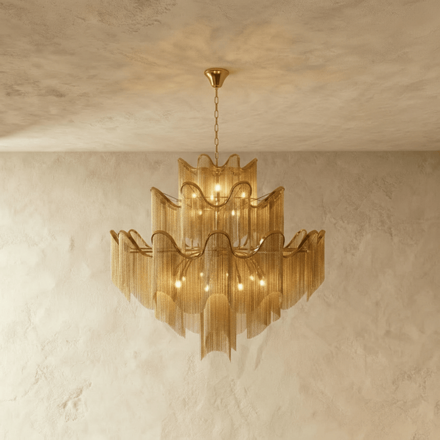 A tiered chandelier of wavy gold bands with fine chain fringe falling below each tier