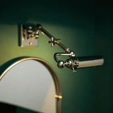 Polished tube lit beside an arched mirror on a deep green painted wall
