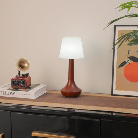 Small walnut lamp lit with a cool white bulb on a wood shelf