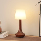 Small walnut lamp lit in a corner against a pale plaster wall
