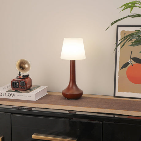 Small walnut lamp lit brightly on a shelf against a pale wall