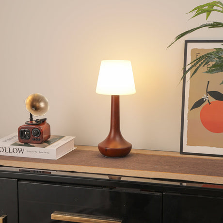 Small walnut lamp lit softly on a shelf beside stacked books