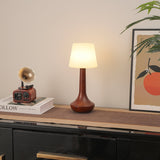 Small walnut lamp lit on a shelf beside a brass gramophone ornament
