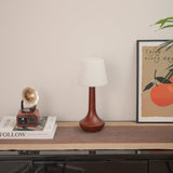 Small walnut lamp unlit on a shelf beside small brass objects