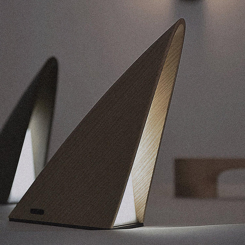Small bedside lamp in the dark finish lit against a pale gray background