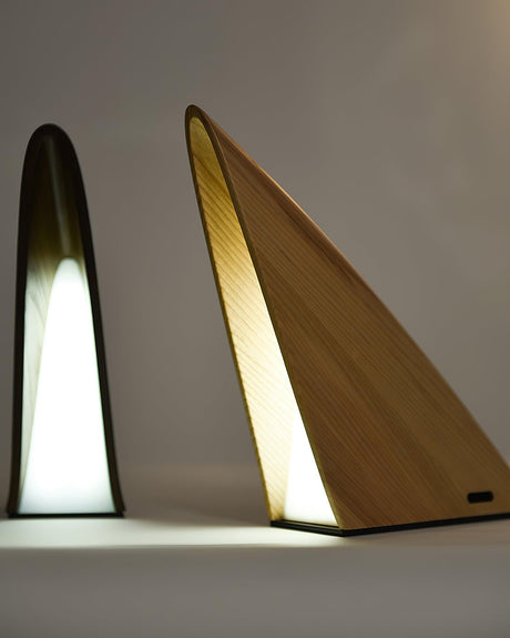 The two wood finishes of the small bedside lamp lit side by side