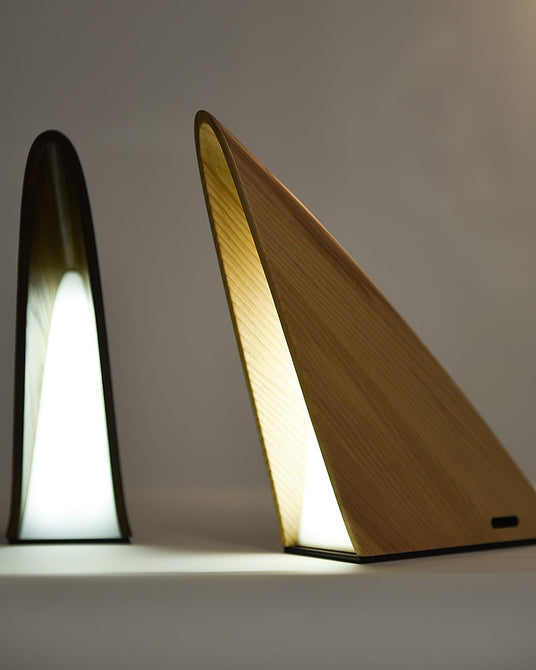 The two wood finishes of the small bedside lamp lit side by side