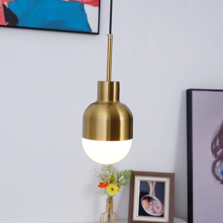 The brass pendant lit beside a bright artwork and a vase of flowers