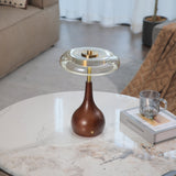 Small table lamp lit on a marble table seen across a pale room