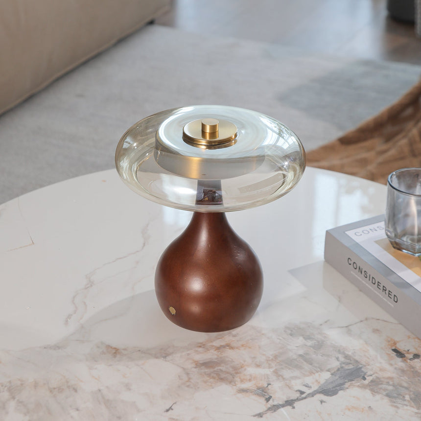 Small table lamp lit on a marble table in front of a sheer curtain