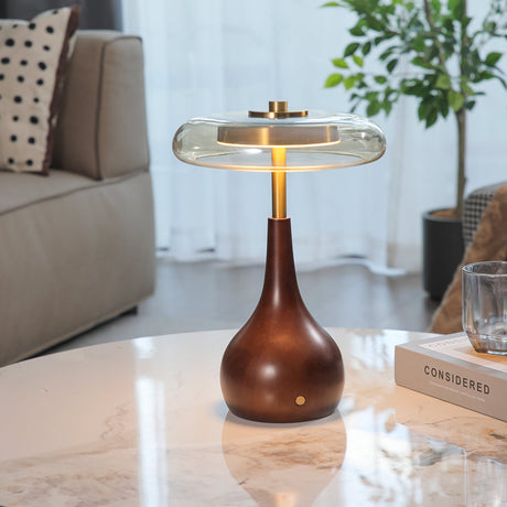 Small table lamp lit on a marble table beside a potted plant