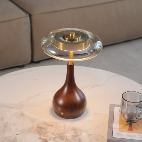 Small table lamp lit on a marble table beside a glass and a book