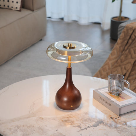 Small table lamp lit on a marble table beside a clear glass mug