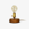 Small table lamp with an exposed bulb on a round solid wood base