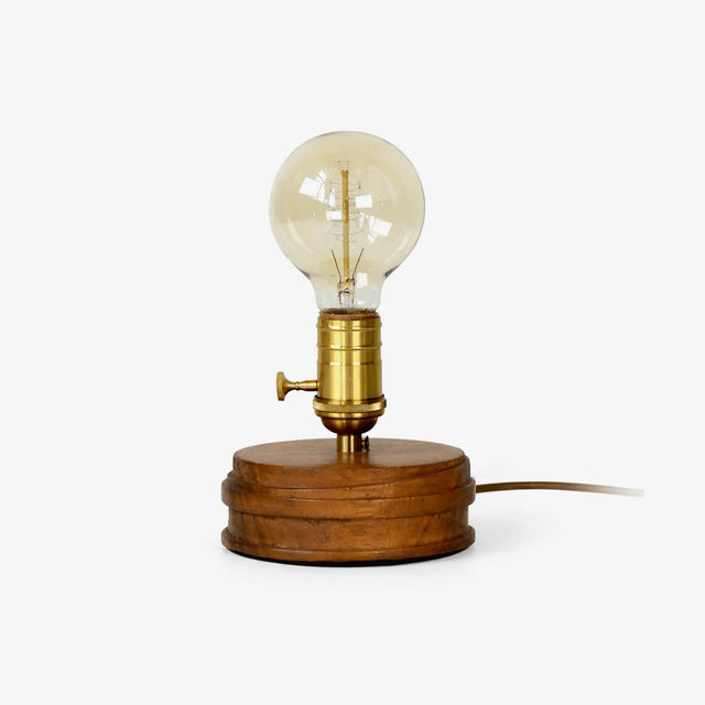Small table lamp with an exposed bulb on a round solid wood base