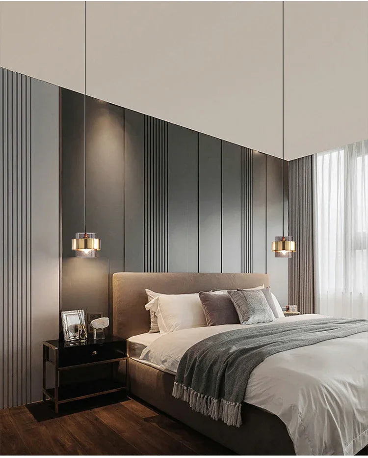 A banded pendant lit on a pale bedroom wall above a wooden unit