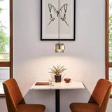 A banded pendant lit above a small cafe table with two tan chairs