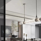 The row of smoked glass tubes lit above a dining table in a pale room
