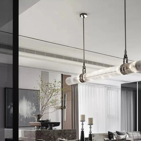 The row of smoked glass tubes lit above a dining table in a pale room
