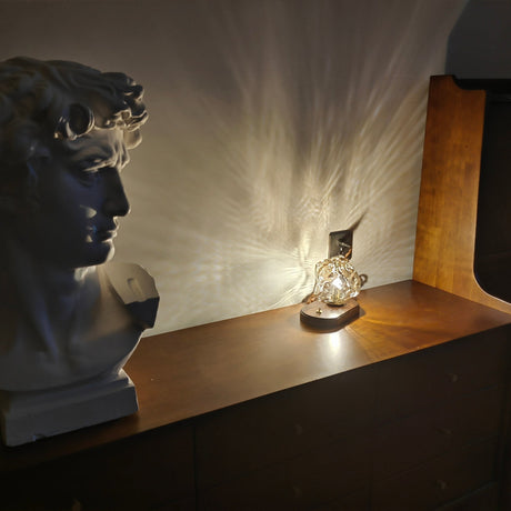 Glass ice form lamp lit beside a plaster bust, shadows on the wall