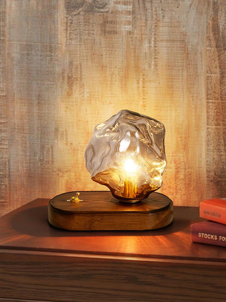 Glass ice form lamp lit against a warm textured wall